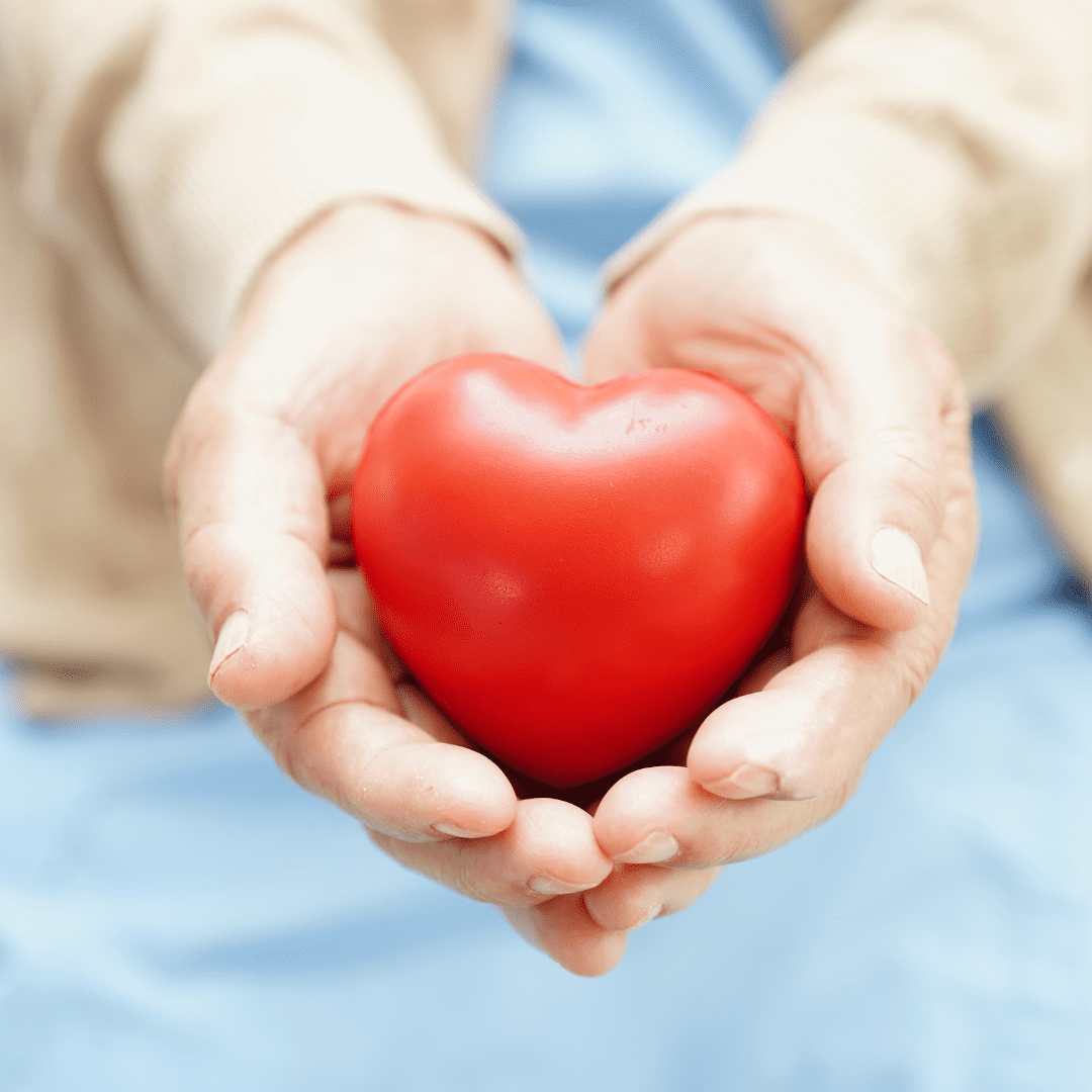 Mãos segundo um coração vermelho brilhante.