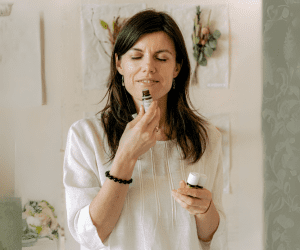 mulher com óleos essenciais na mão e cheirando um frasco