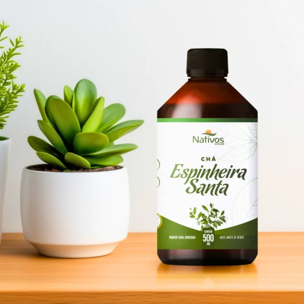 Frasco de Espinheira Santa líquida sobre bancada de madeira com planta decorativa ao lado, sugerindo naturalidade e bem-estar.